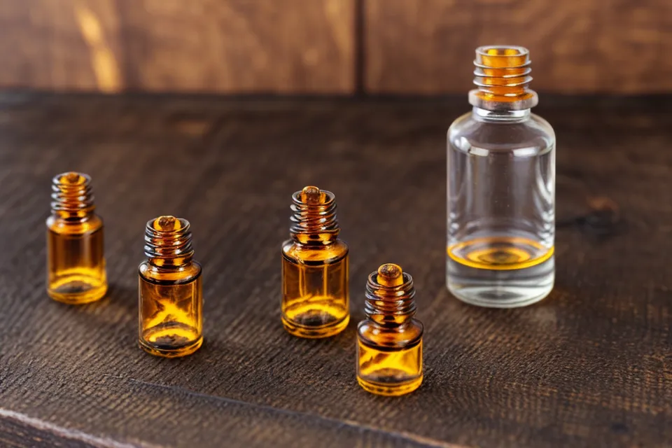 Écran d'ordinateur affichant un schéma de distillation à côté d'un flacon d'huile essentielle.
